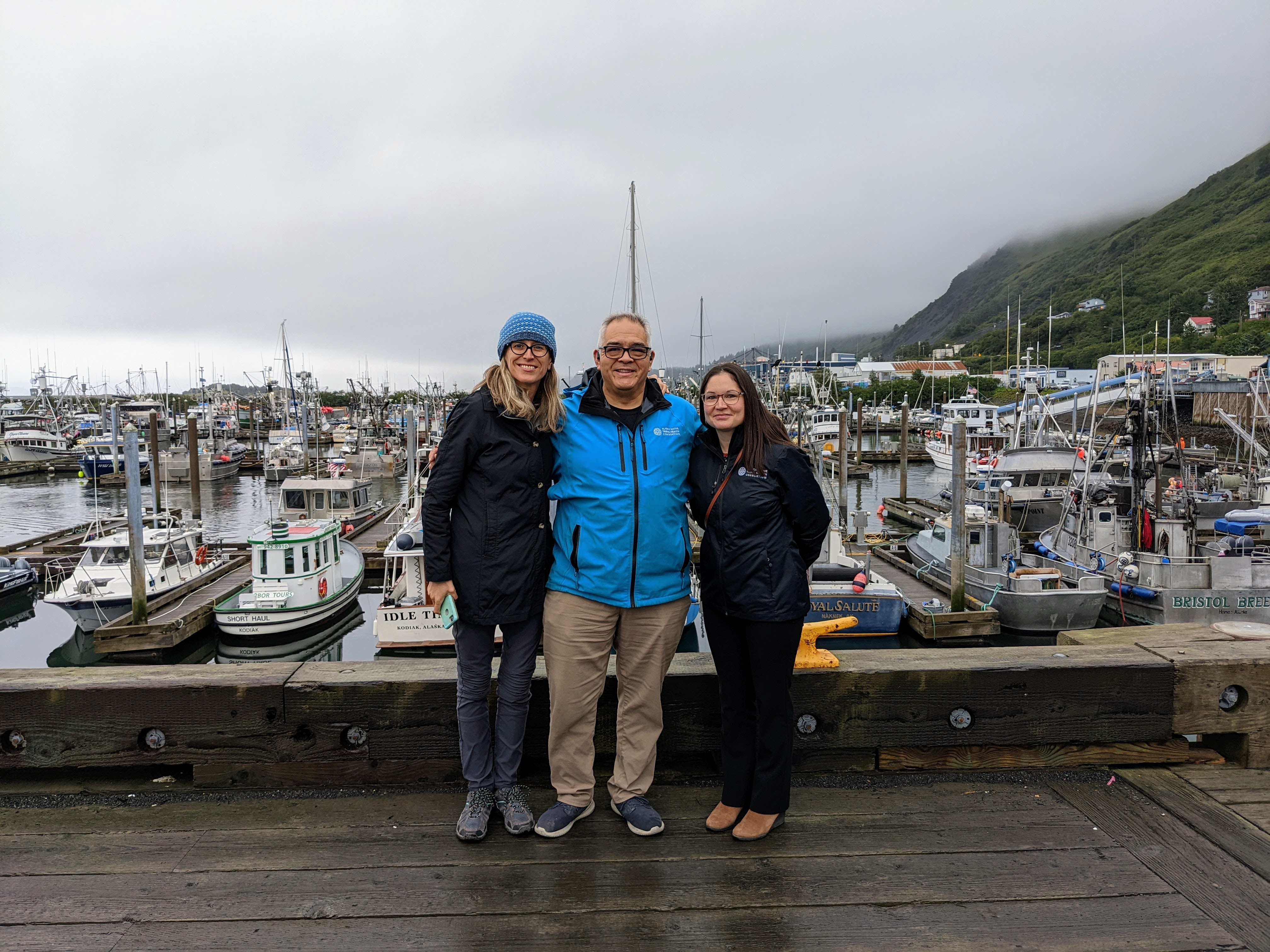 three people standing in front of a marina full of boats