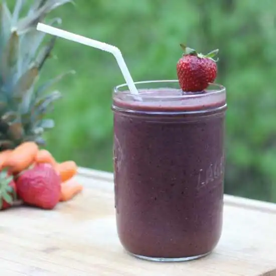 glass with a purple smoothie and a straw
