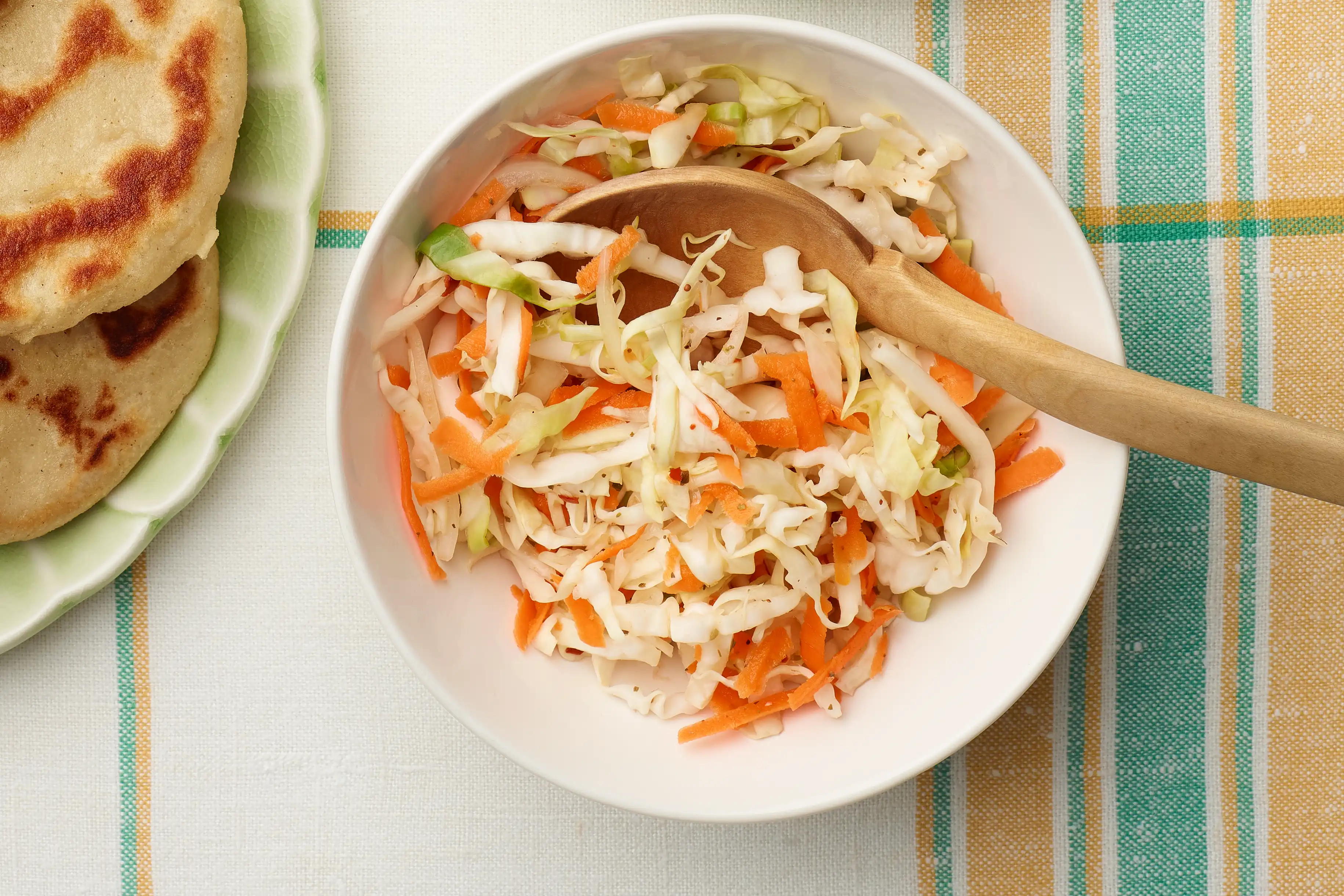bowl of cabbage salad with a wooden spoon in it