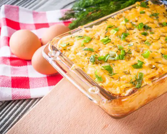 clear baking dish with egg casserole and whole shell eggs to the side