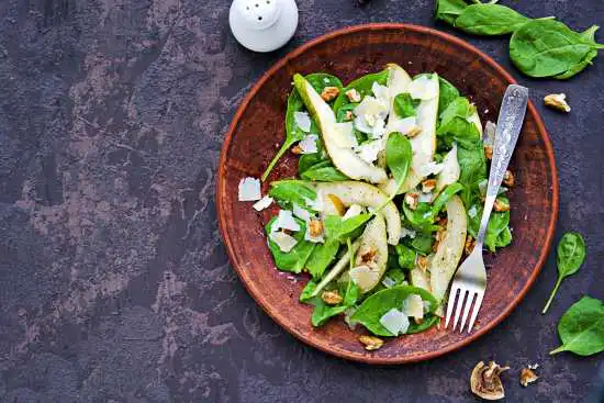photo of a wooden bowl with a salad and pears