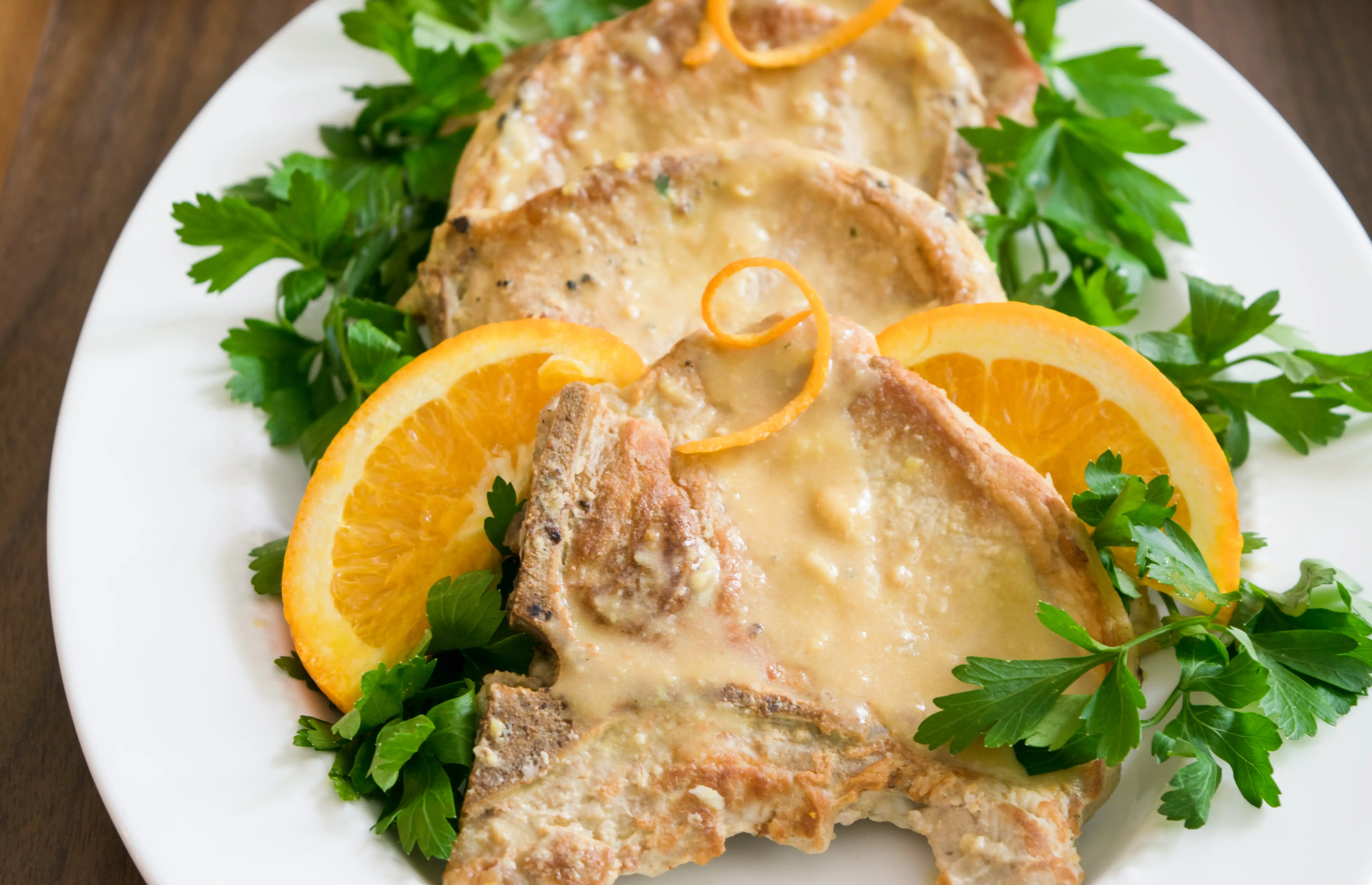 plate with pork chops, greens, and orange slices