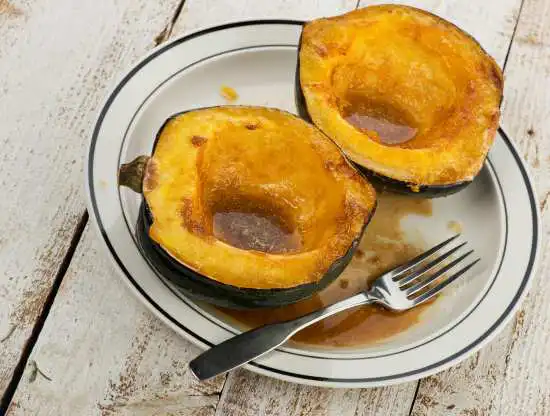 two halves of an acorn squash on a plate with a fork