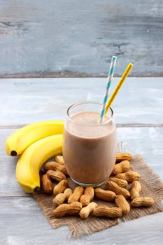 peanut butter banana smoothie with a straw and bananas on the side