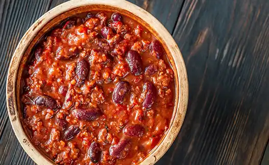 bowl of bison chili on a wooden tabletop