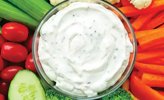 bowl of ranch dip surrounded by veggies
