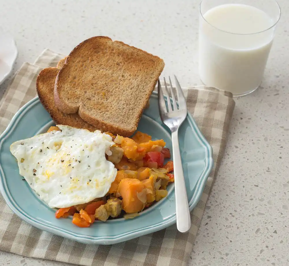 light blue plate with toast, sweet potato hash, and an egg