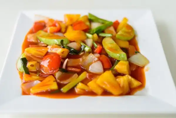 white plate with vegetables in orange sauce