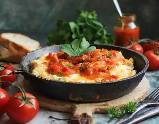 skillet with scrambled eggs and tomatoes