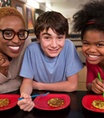 a teacher and two students smiling in front of their plates