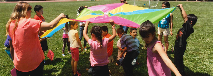 kids playing with a parachute on a grassy lawn