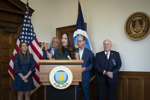 Secretary Rollins speaking at a podium surrounded by other Governors.