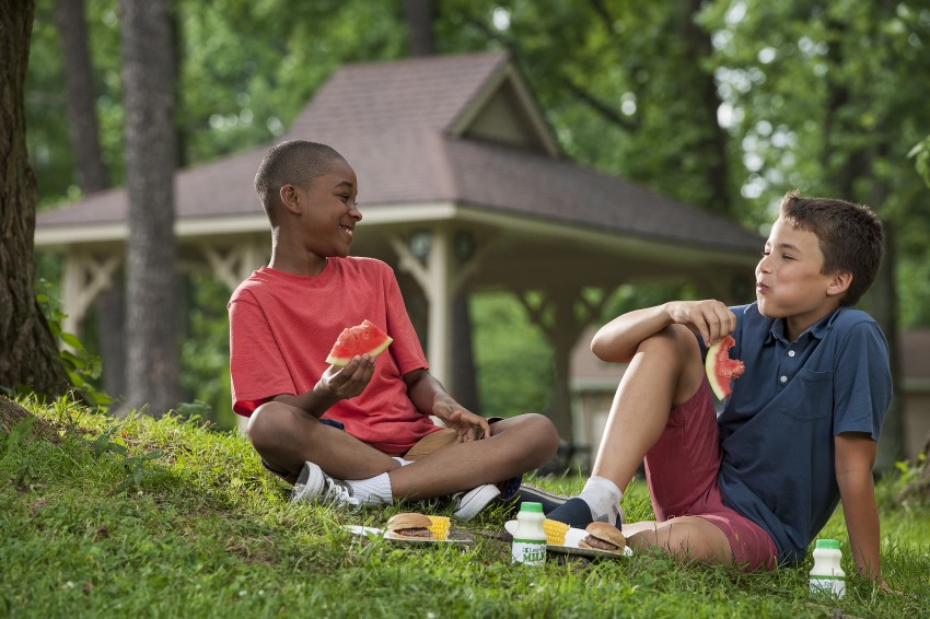 two boys eating in a field