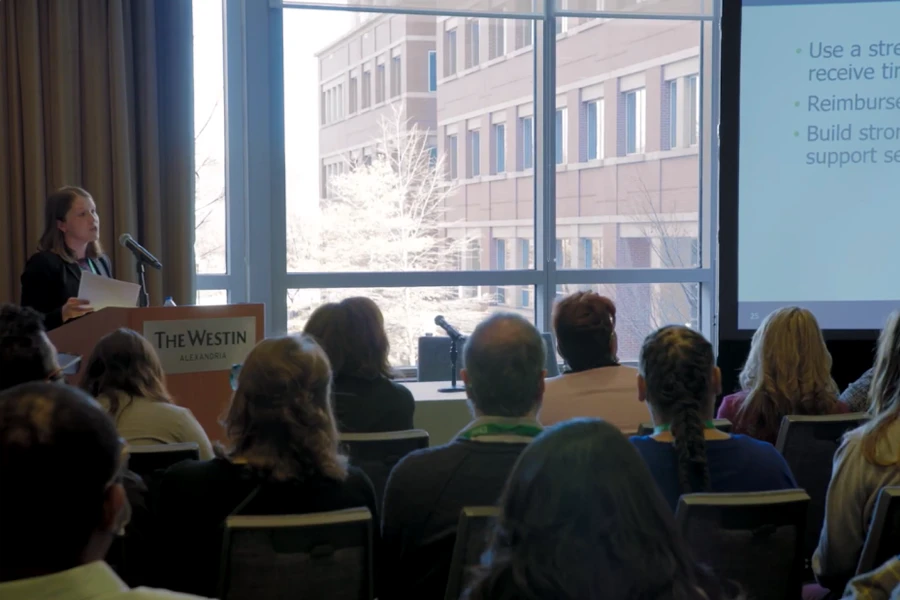 a woman standing at a podium giving a presentation
