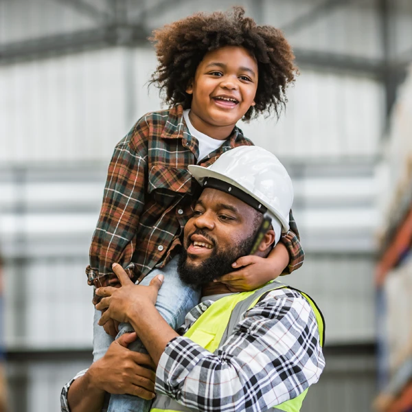 a man in a hard hat holding a child on his shoulder