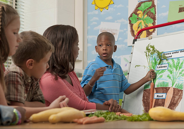 boy in font of class holding a carrot