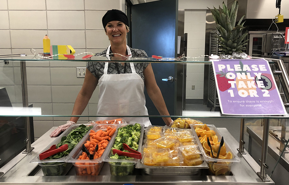 school nutrition professional in front of colorful salad bar