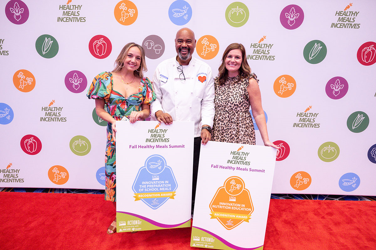 a group of Healthy Meals Incentives Awardees in front of a step and repeat at the 2024 summit