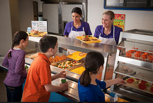 two staff serving school lunch to students in a line