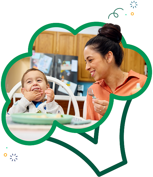 woman feeding her smiling little boy at the table