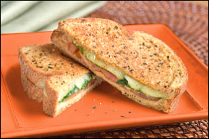 Two grilled cheese sandwich halves with lettuce and tomato