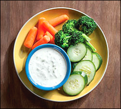 Sliced cucumbers, carrots, broccoli and dip