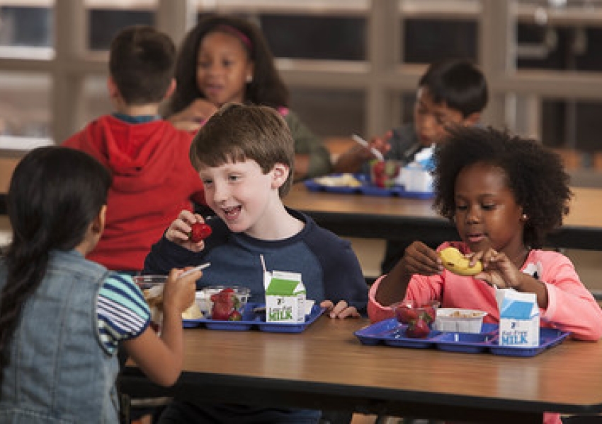 3 kids eating school lunch in a cafeteria