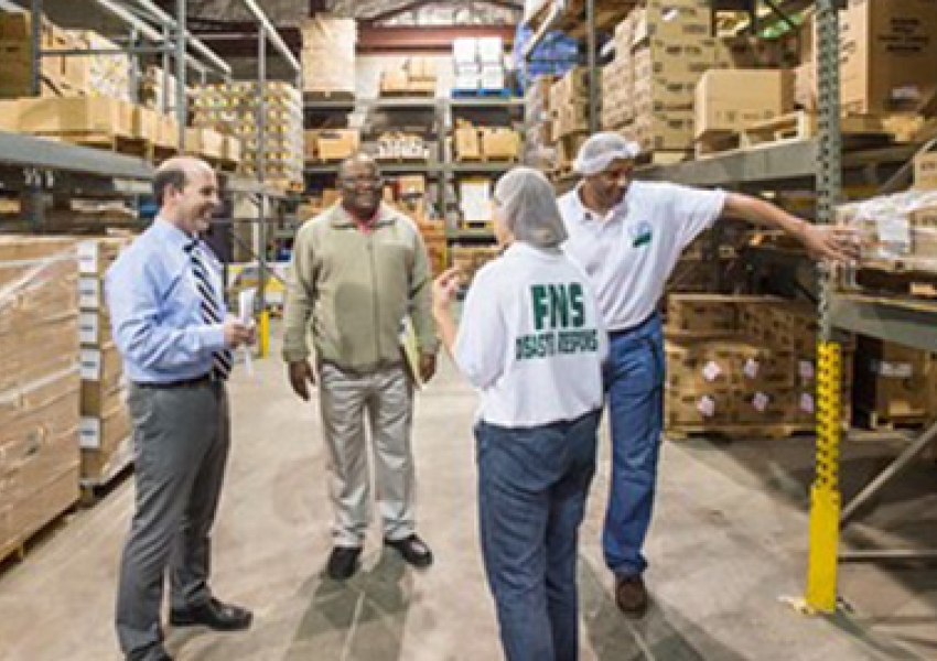 a group of people standing in a warehous with FNS Disaster Response t shirts on