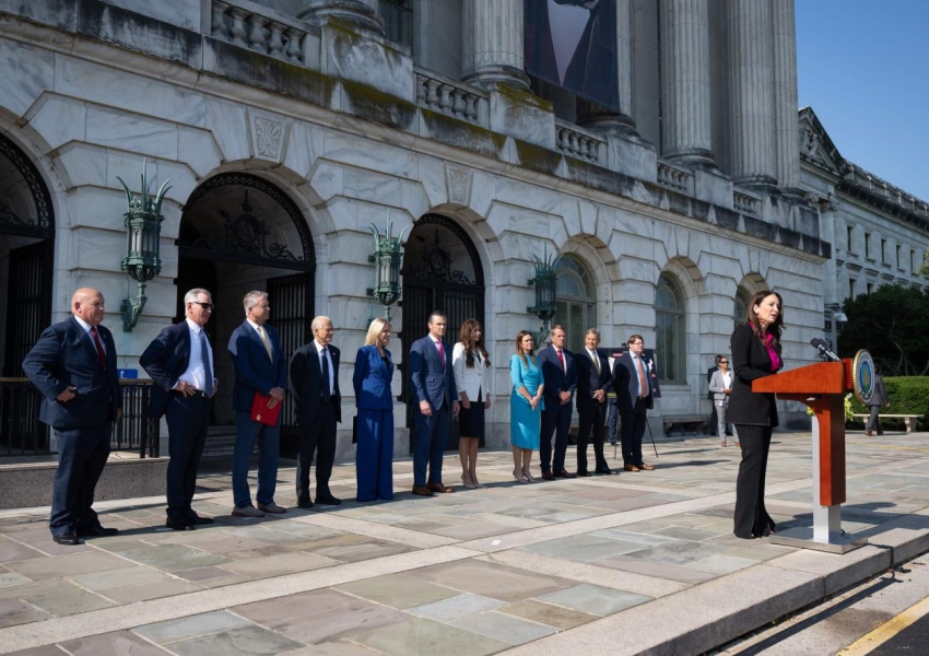 Secretary Rollins standing at a podium speaking with other governors and secretaries behind her.