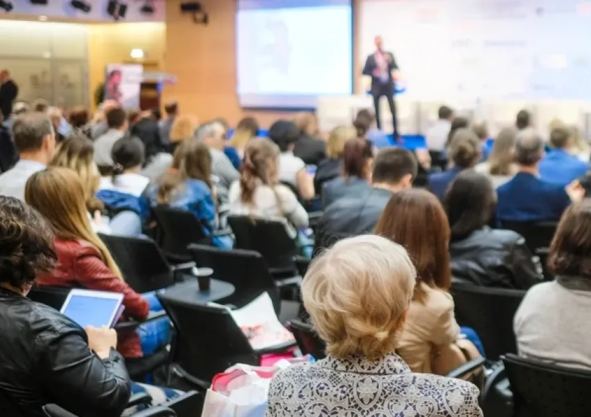 a roomful of people attending a conference listening to a speaker