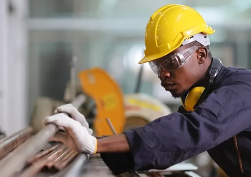 man in a yellow hard hat working on pipes