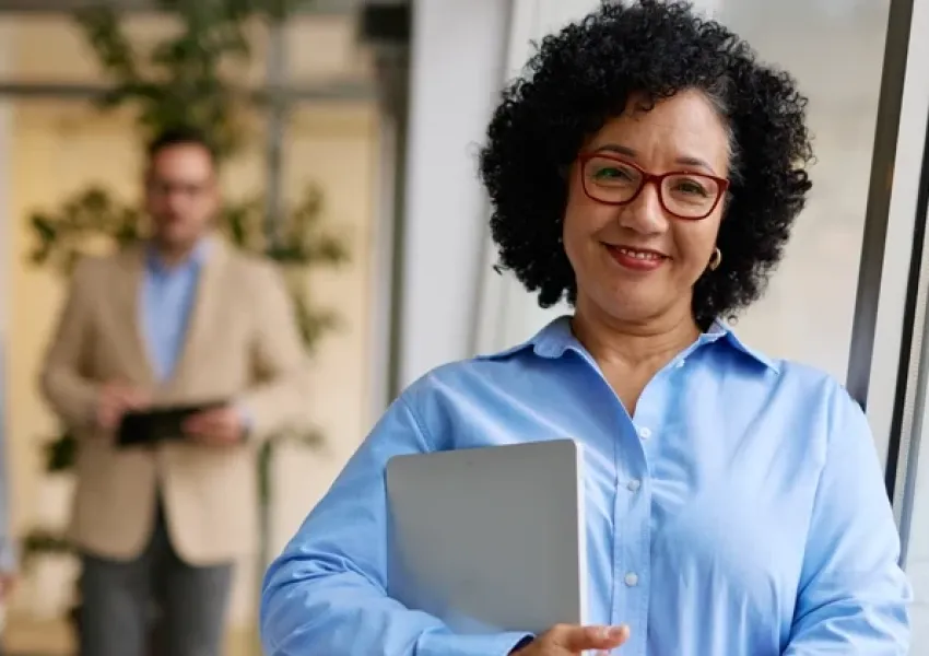 a woman leaning against a wall holding a notebook