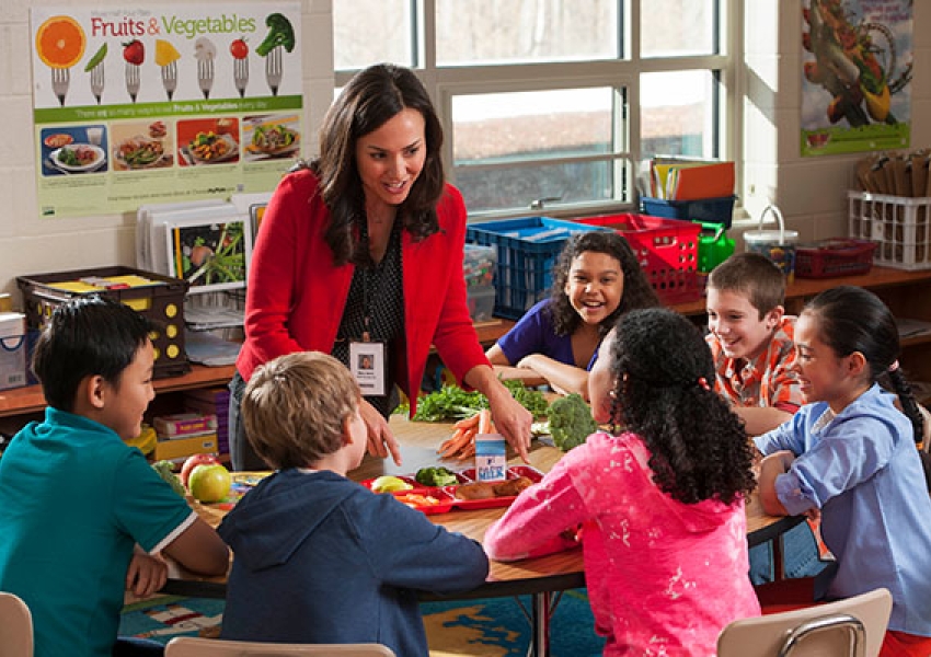 a teacher showing children a healthy meal in a classroom