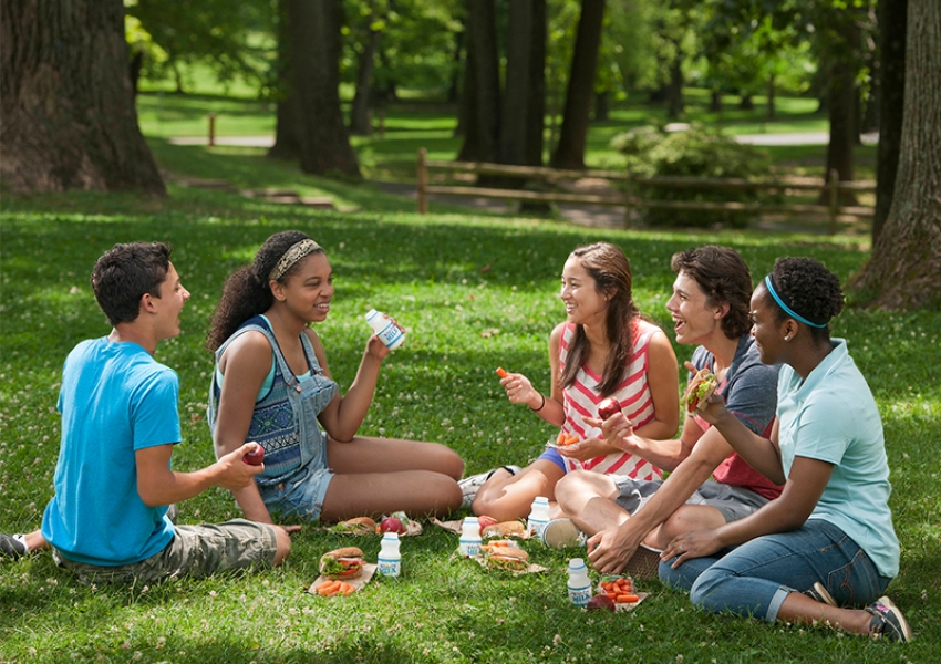 a group of teens eating lunch outside at a summer meals site