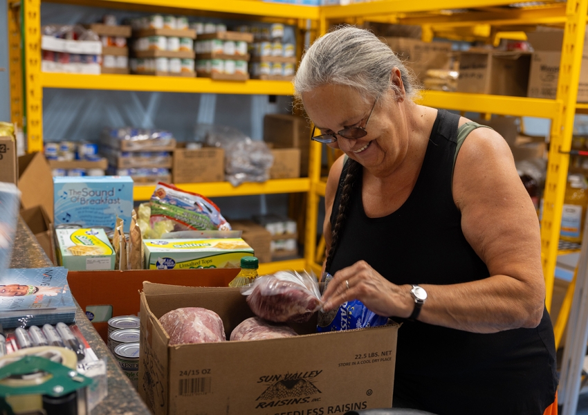 a woman smiling while looking into a box of foods