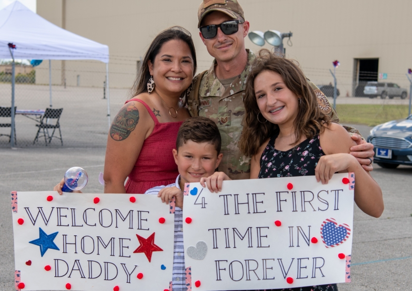 picture of military father coming home to wife and kids with welcome posters