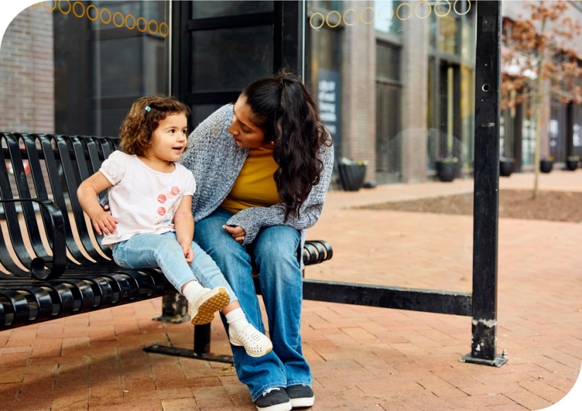 a woman and a child sitting on a bus stop bench
