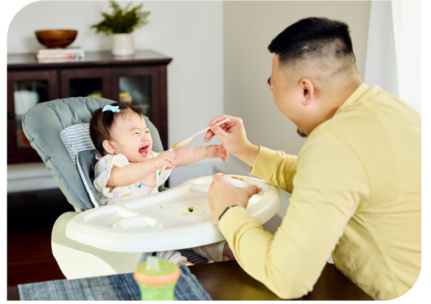man feeding his infant in a highchair
