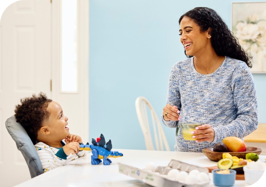 a woman and her son preparing a meal at the kitchen counter while laughing together