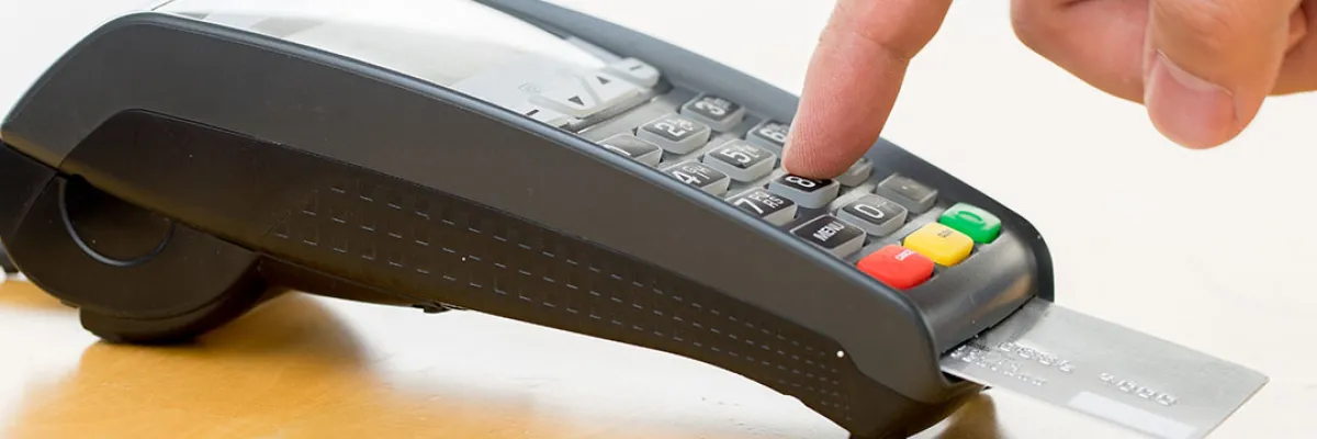 fingers typing a pin into a card transaction machine