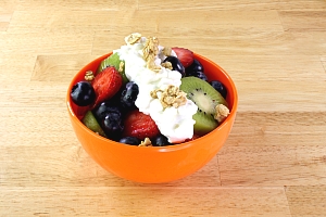 orange bowl with a variety of fruit topped with cottage cheese