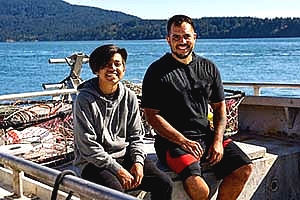 image of an adult man and a younger man on a fishing boat smiling