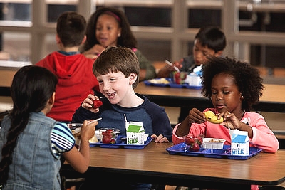 3 kids eating school lunch in a cafeteria