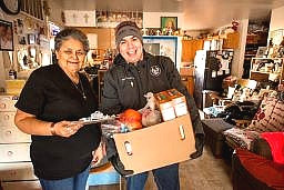 fdpir home delivery with a woman holding a clipboard smiling next to young man delivery a box of food