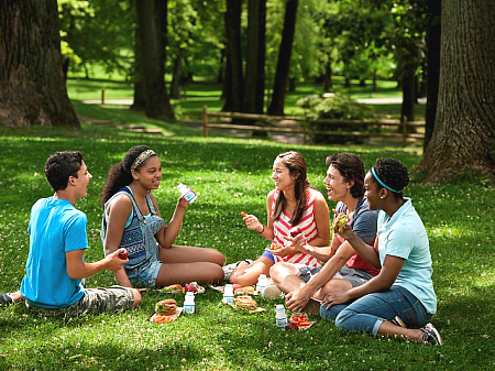 kids enjoying a summer meal on a green lawn