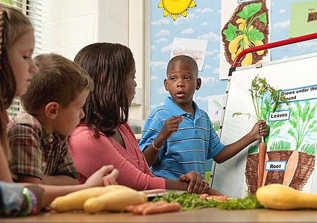 boy in font of class holding a carrot